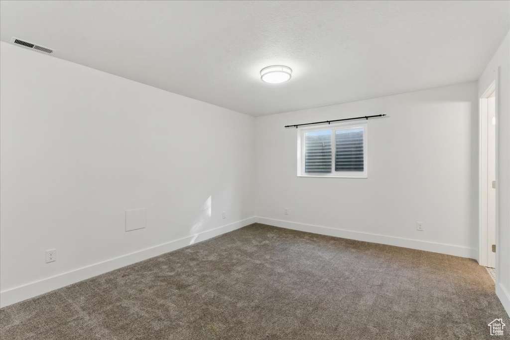 Unfurnished room with dark carpet and baseboards