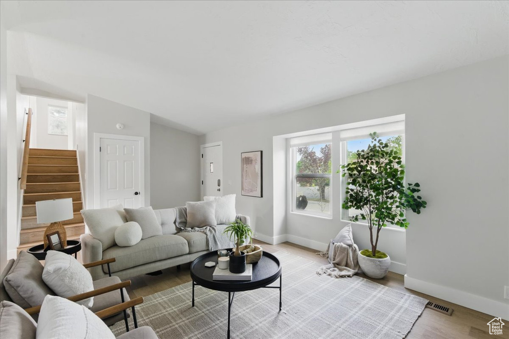Living area featuring baseboards, light wood finished floors, stairway, and lofted ceiling