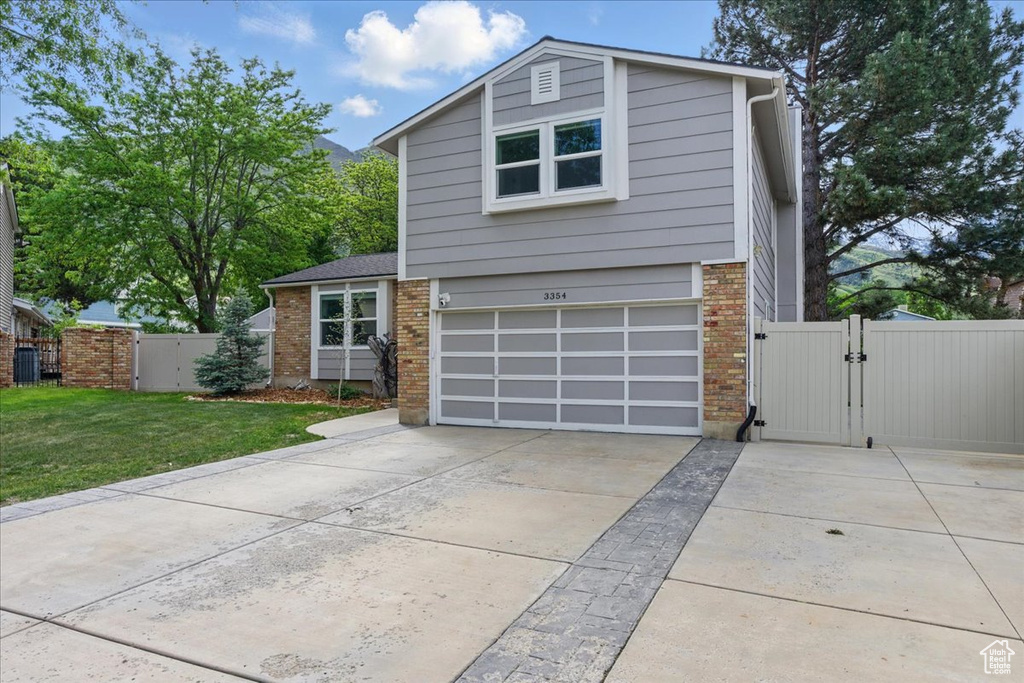 View of front of home featuring a gate, driveway, brick siding, and an attached garage