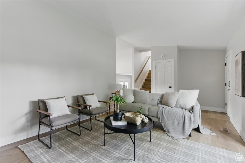 Living room with stairs, light wood-style flooring, and baseboards