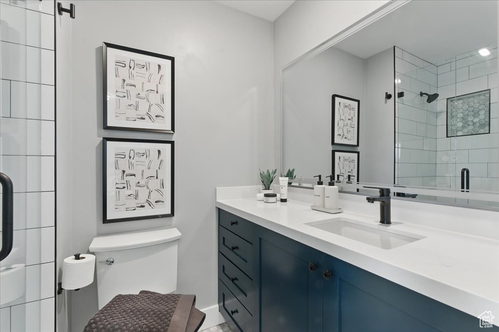 Full bathroom featuring tiled shower, toilet, vanity, and baseboards