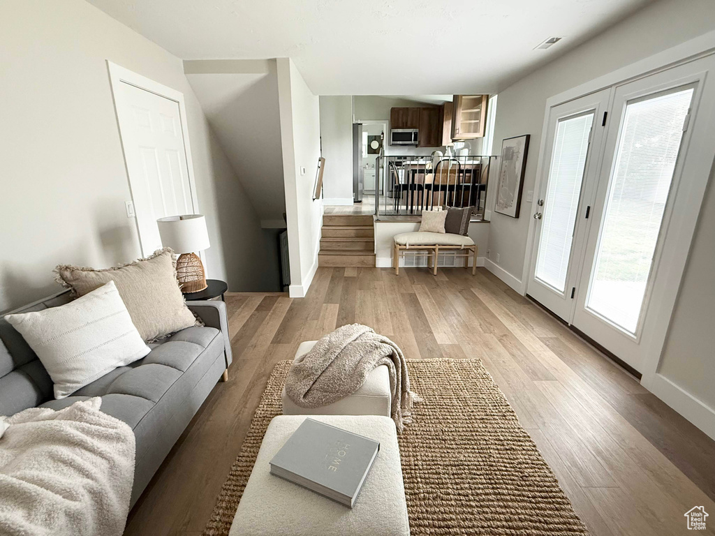 Living room featuring light wood-type flooring, stairs, and baseboards