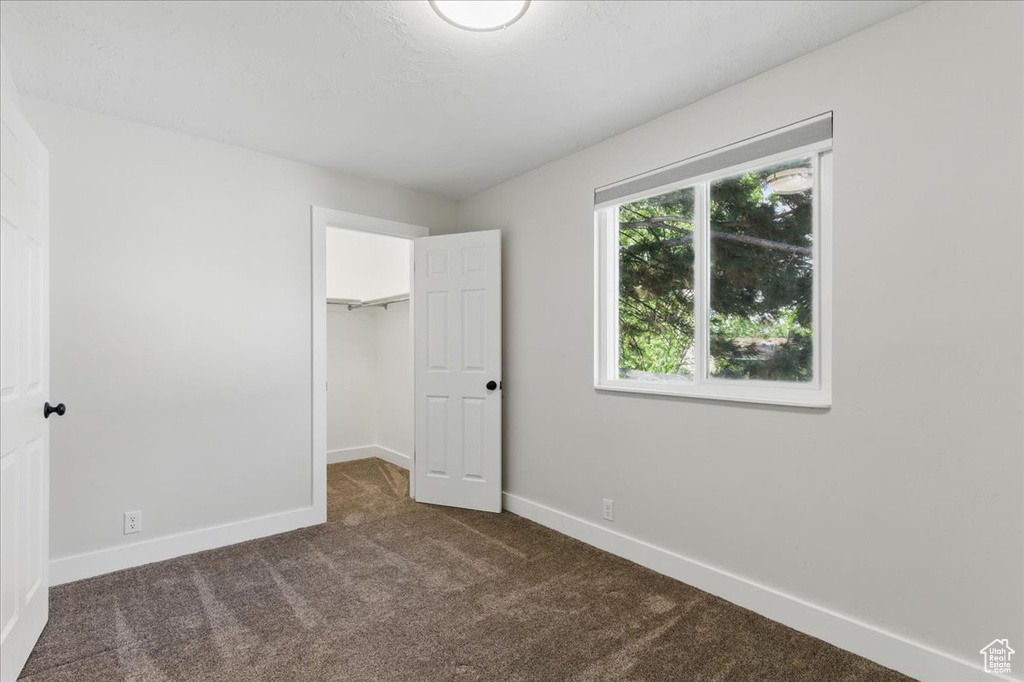 Unfurnished bedroom with carpet floors, baseboards, a spacious closet, and a closet