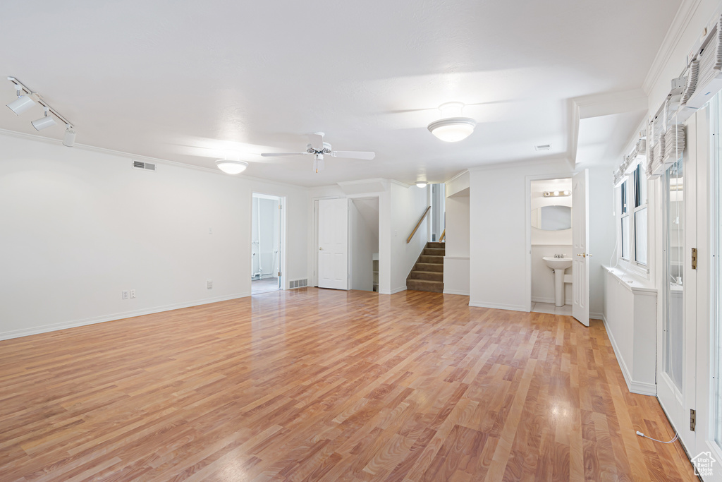 Spare room featuring stairs, light wood-style floors, ceiling fan, and baseboards