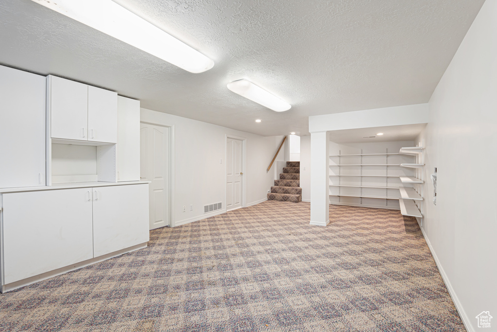 Finished basement with baseboards, a textured ceiling, carpet, stairway, and recessed lighting