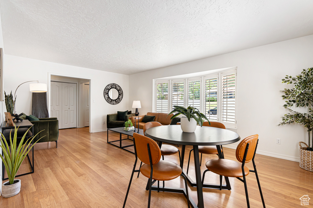 Dining room with a textured ceiling, light wood-style flooring, and baseboards