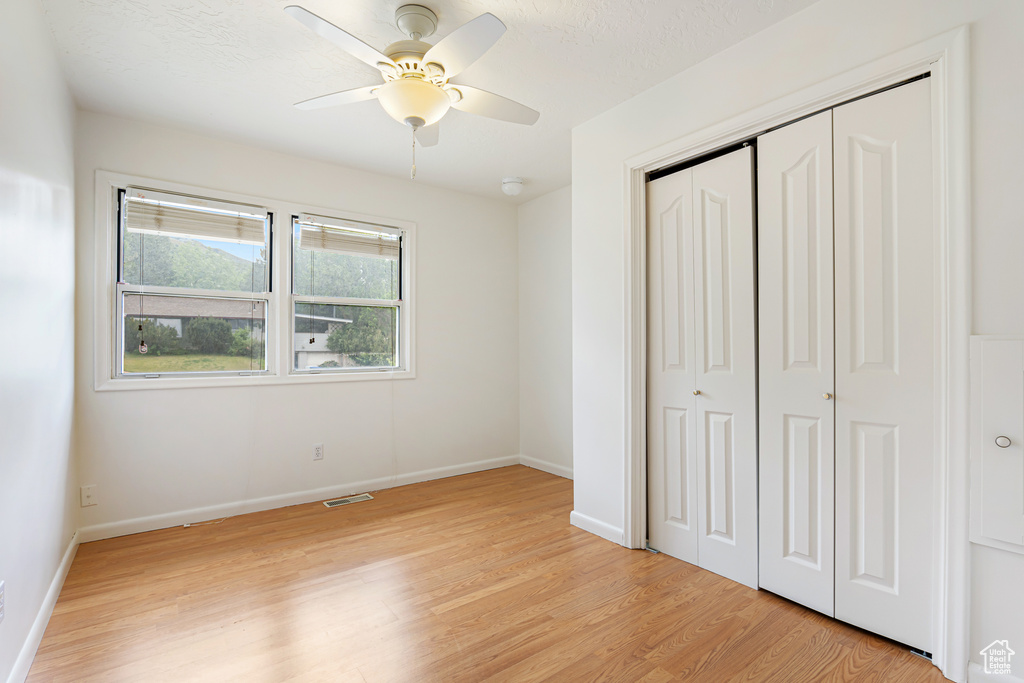 Unfurnished bedroom featuring light wood-style floors, a closet, baseboards, and ceiling fan