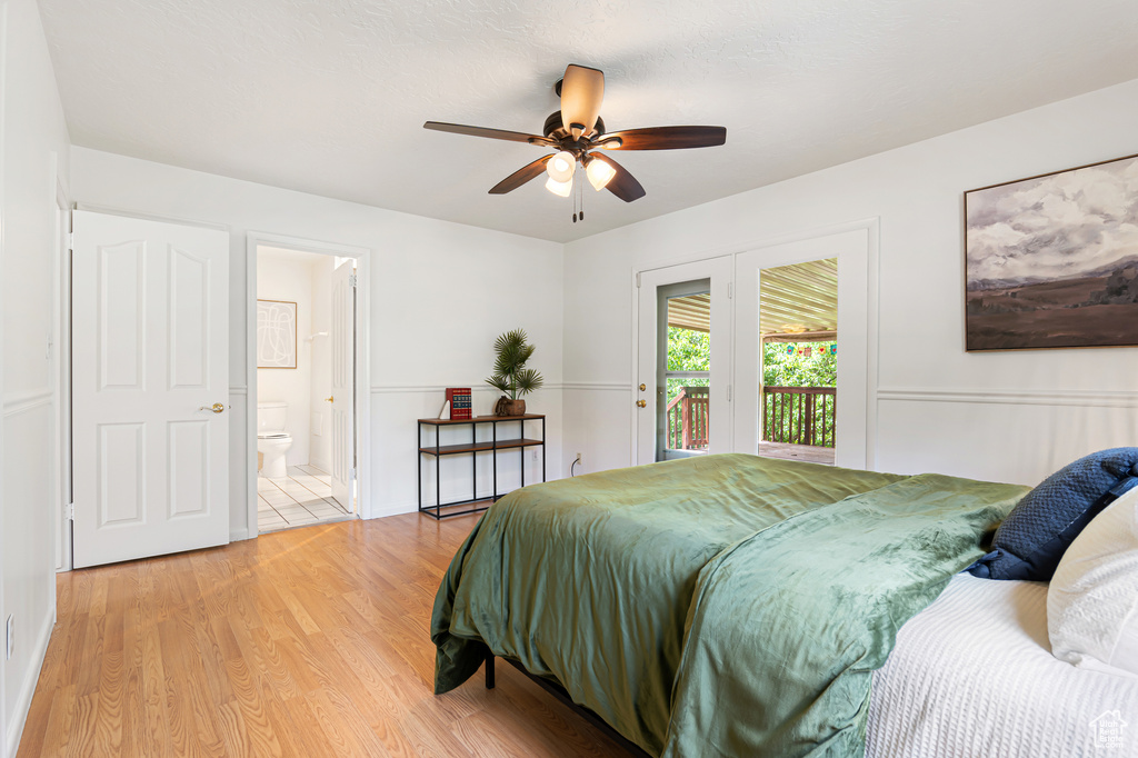Bedroom featuring access to exterior, light wood-style flooring, ensuite bath, and a ceiling fan