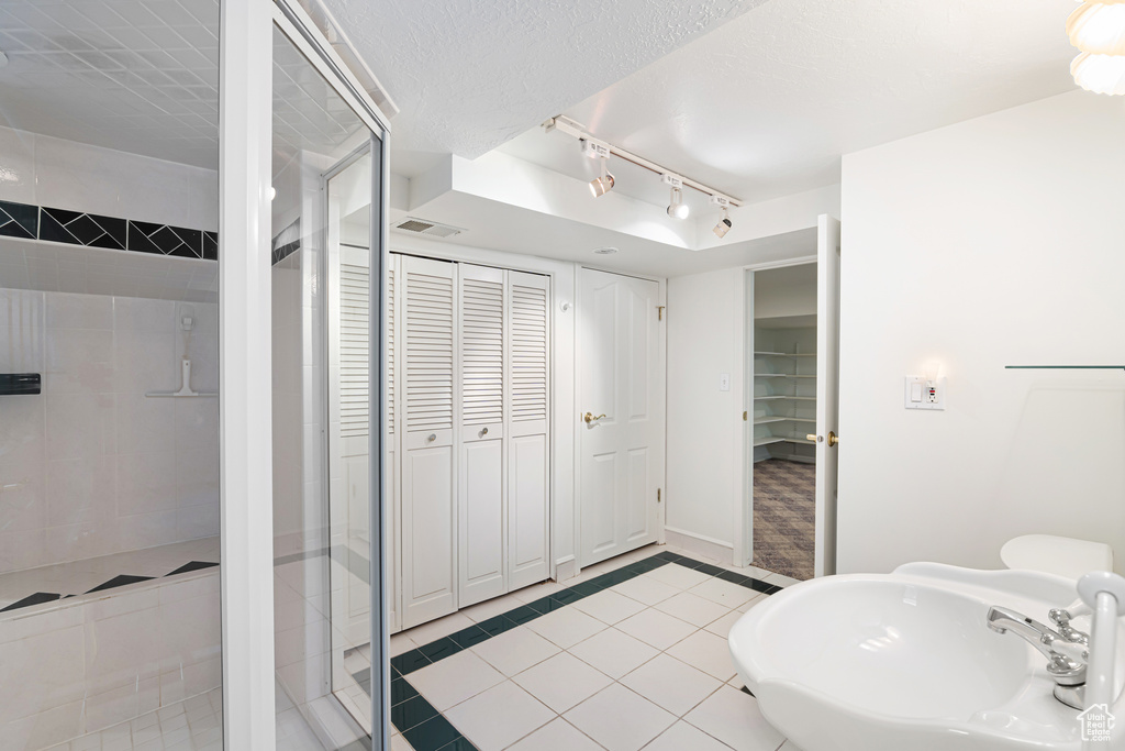 Full bath with a sink, track lighting, a shower stall, and a closet