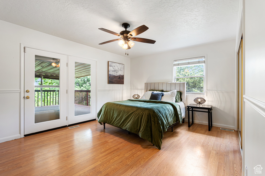 Bedroom with access to outside, light wood-style flooring, a textured ceiling, and ceiling fan