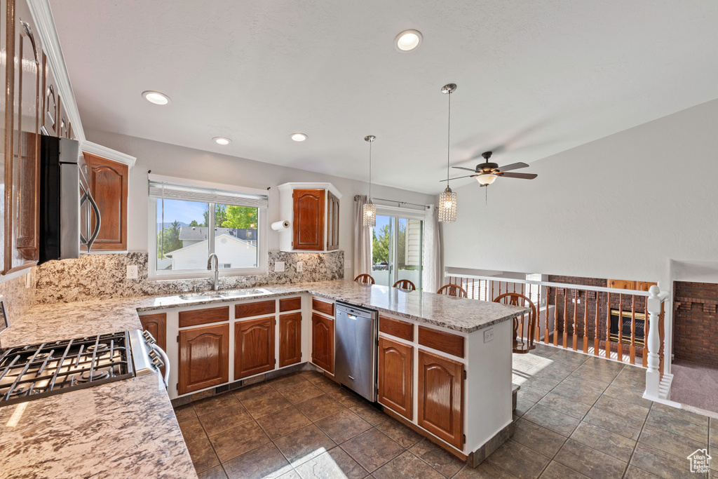 Kitchen featuring appliances with stainless steel finishes, ceiling fan, a peninsula, backsplash, and a sink