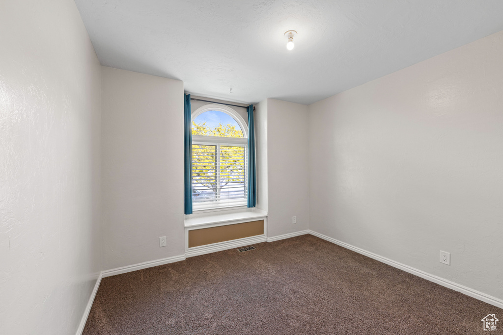 Unfurnished room featuring dark colored carpet and baseboards