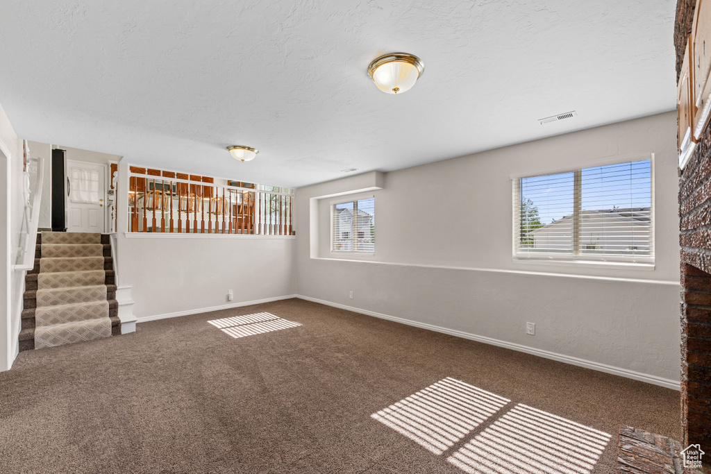 Basement with baseboards, stairs, carpet floors, and a textured ceiling