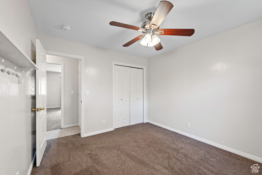 Unfurnished bedroom with carpet floors, baseboards, a closet, and a ceiling fan