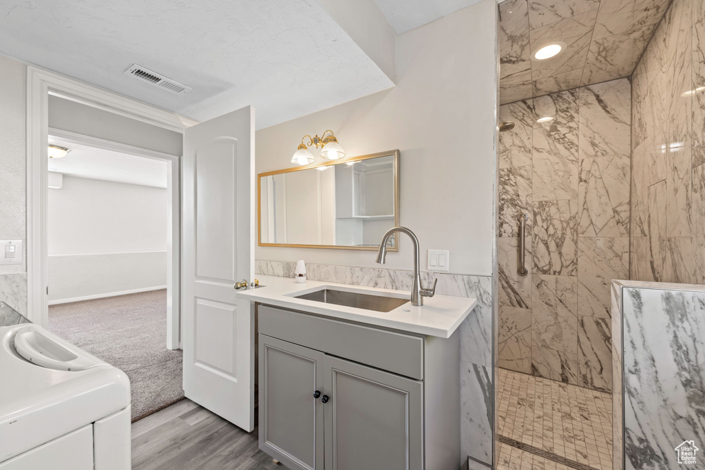 Bathroom featuring a marble finish shower, vanity, and wood finished floors