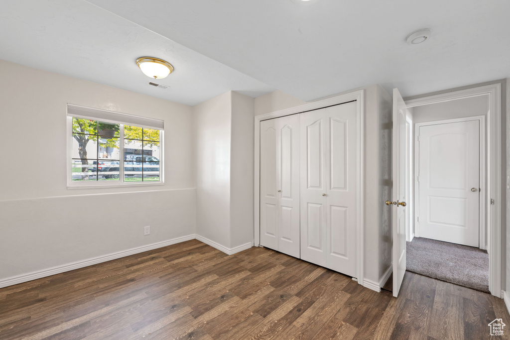 Unfurnished bedroom with dark wood-type flooring, baseboards, and a closet