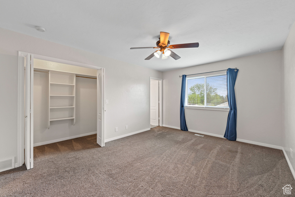 Unfurnished bedroom with carpet, baseboards, a ceiling fan, and a closet