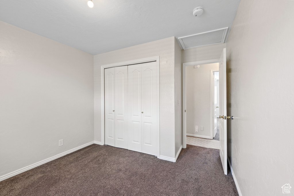 Unfurnished bedroom with dark carpet, baseboards, and a closet