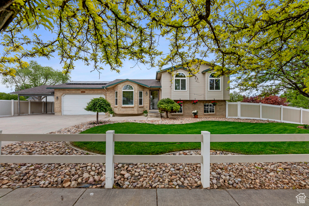 Tri-level home featuring brick siding, concrete driveway, solar panels, and a garage