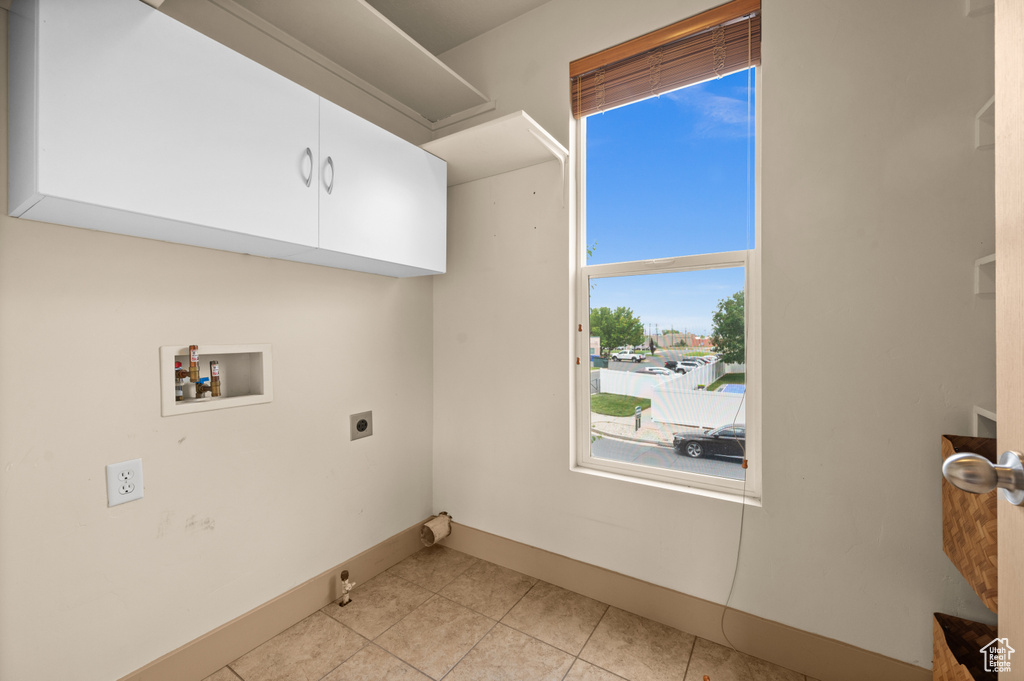 Laundry area featuring cabinet space, washer hookup, electric dryer hookup, baseboards, and light tile patterned floors