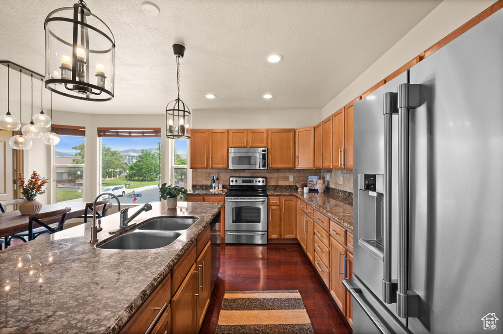 Kitchen with appliances with stainless steel finishes, a sink, a chandelier, recessed lighting, and backsplash