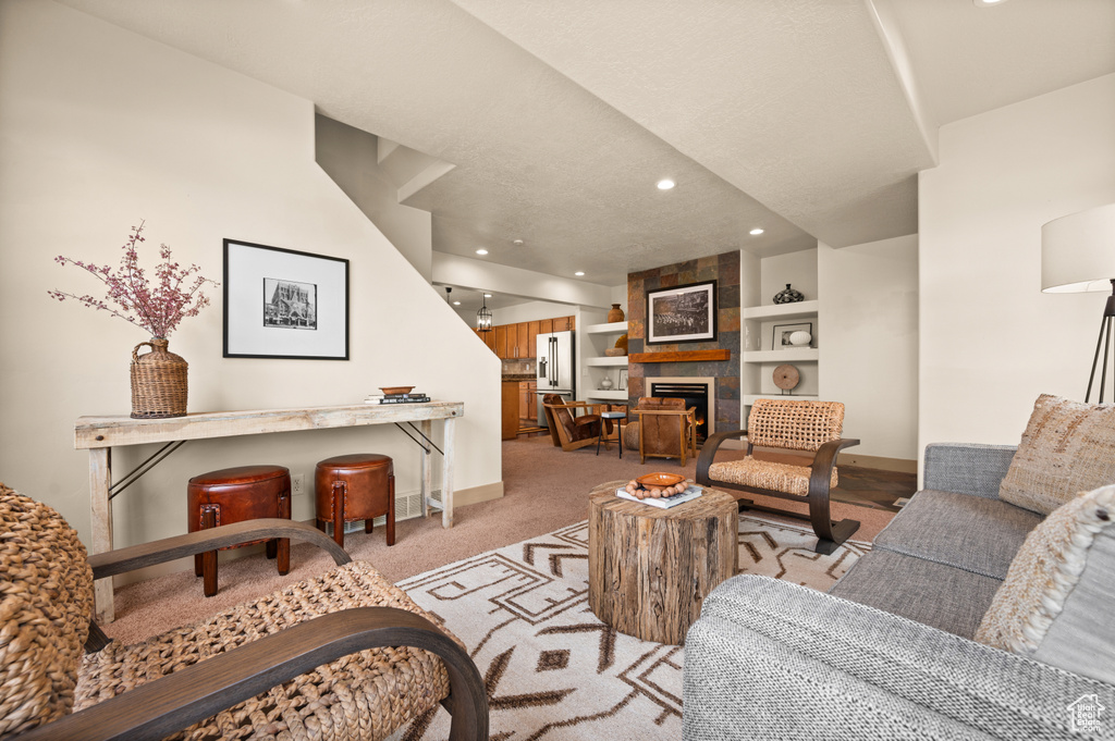 Living area featuring baseboards, built in features, a large fireplace, recessed lighting, and light colored carpet