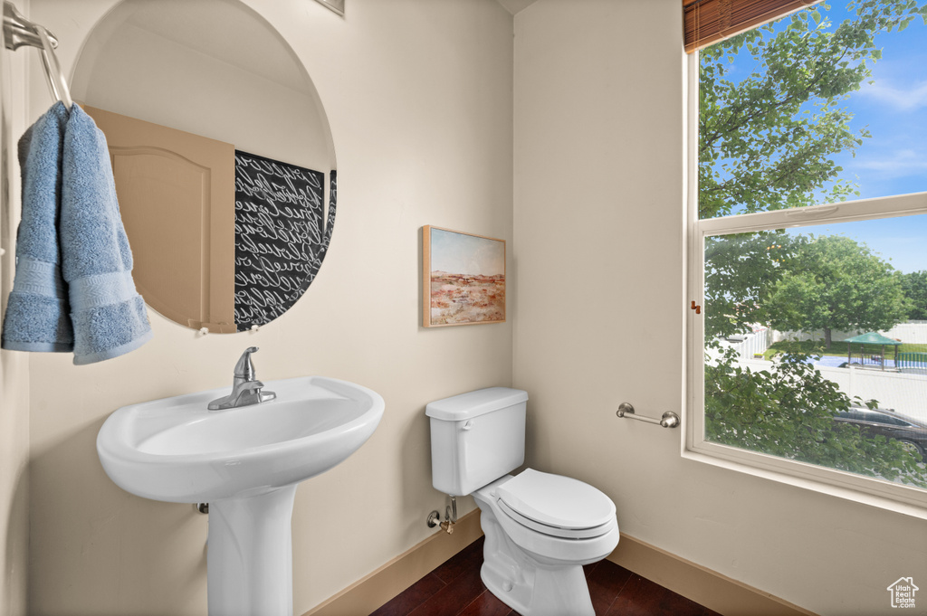 Bathroom featuring baseboards, healthy amount of natural light, toilet, and wood finished floors