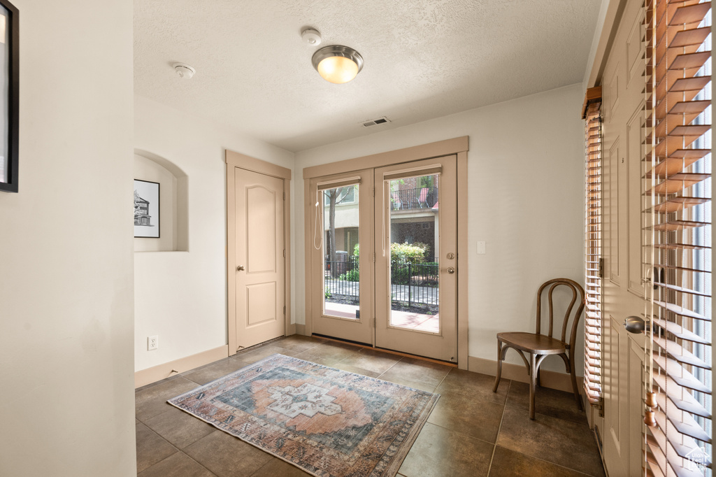 Doorway to outside with a textured ceiling, french doors, baseboards, and tile patterned floors