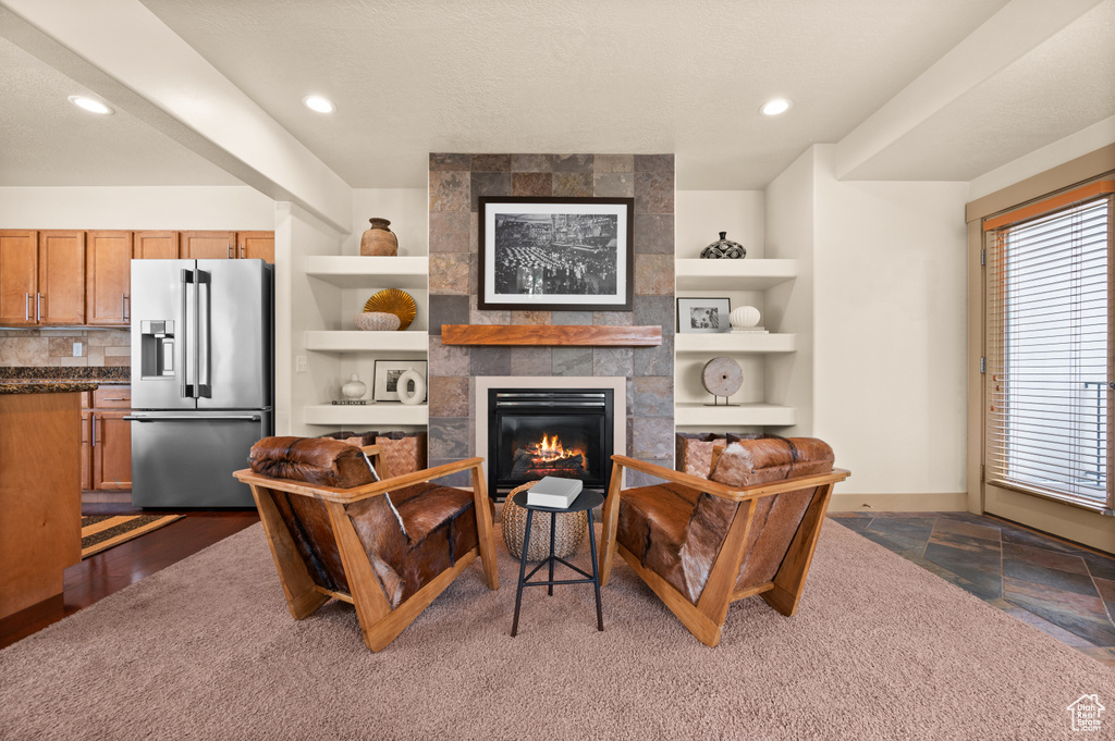 Living area with built in features, a tiled fireplace, recessed lighting, and baseboards