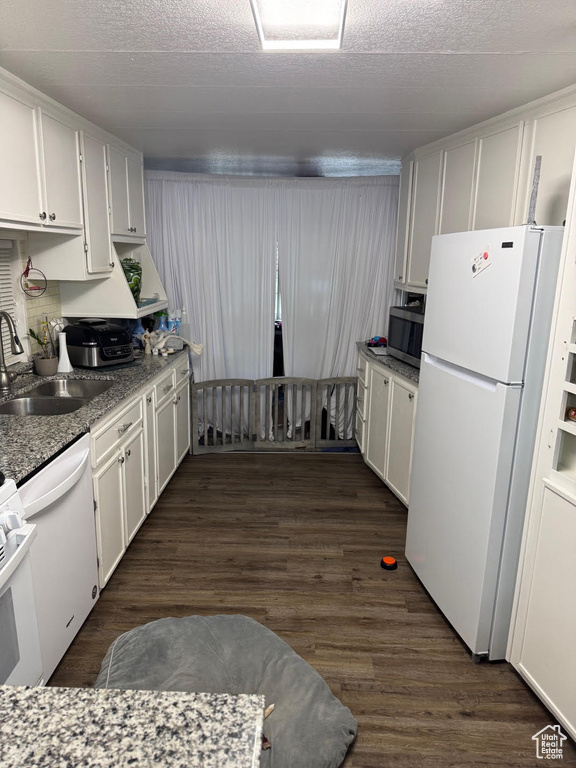 Kitchen featuring white appliances, dark wood-style floors, white cabinetry, a sink, and a textured ceiling
