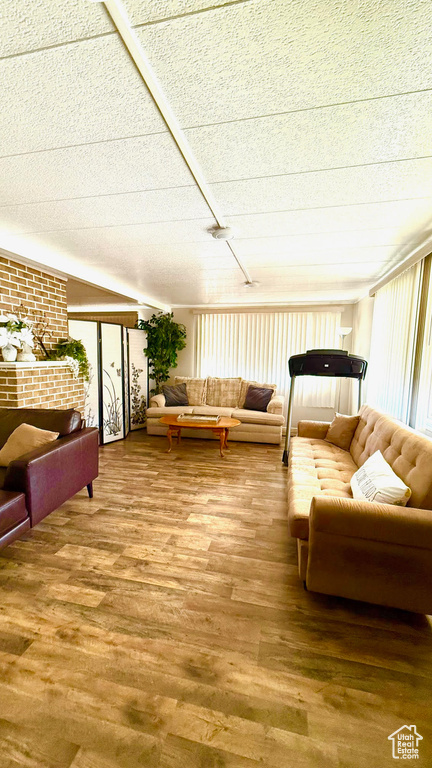 Living area featuring wood finished floors, plenty of natural light, and brick wall