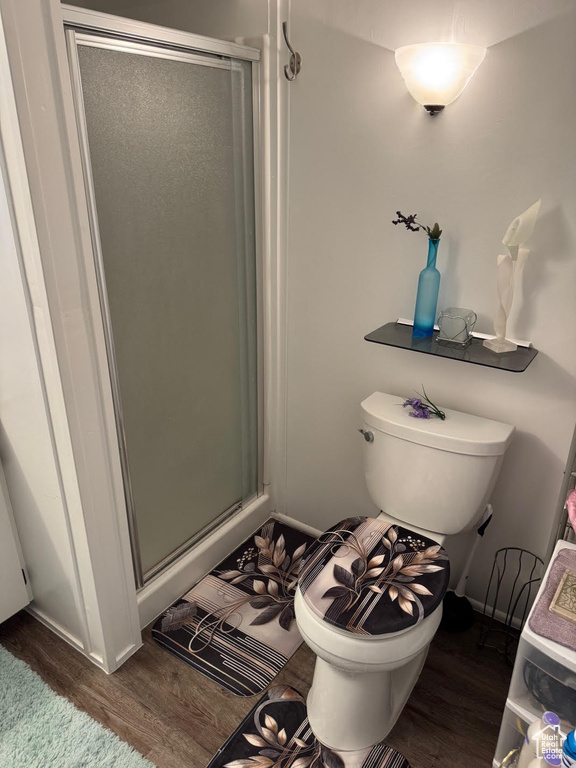 Full bathroom with wood finished floors, a shower stall, and toilet