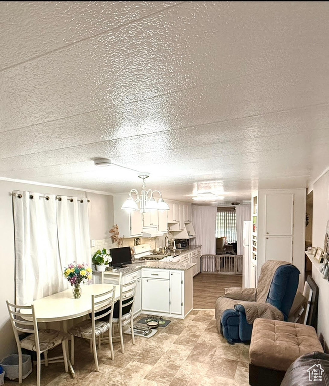 Kitchen with open floor plan, white cabinets, light countertops, a chandelier, and pendant lighting