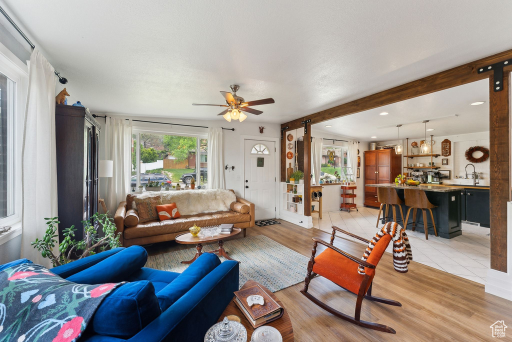 Living room with ceiling fan, light wood-style floors, beam ceiling, and recessed lighting