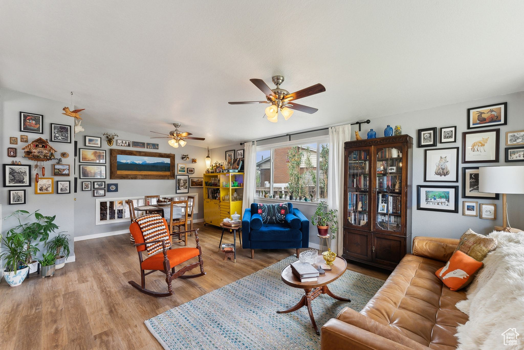 Living area featuring wood finished floors, a ceiling fan, and baseboards