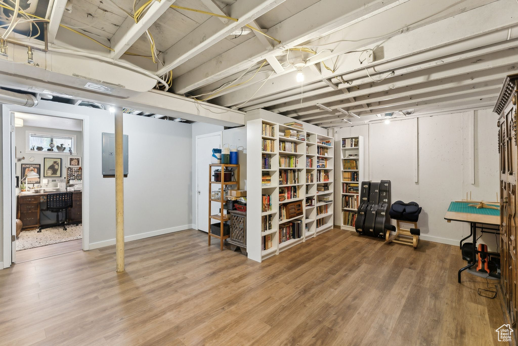 Below grade area with wood finished floors, electric panel, baseboards, and an office area