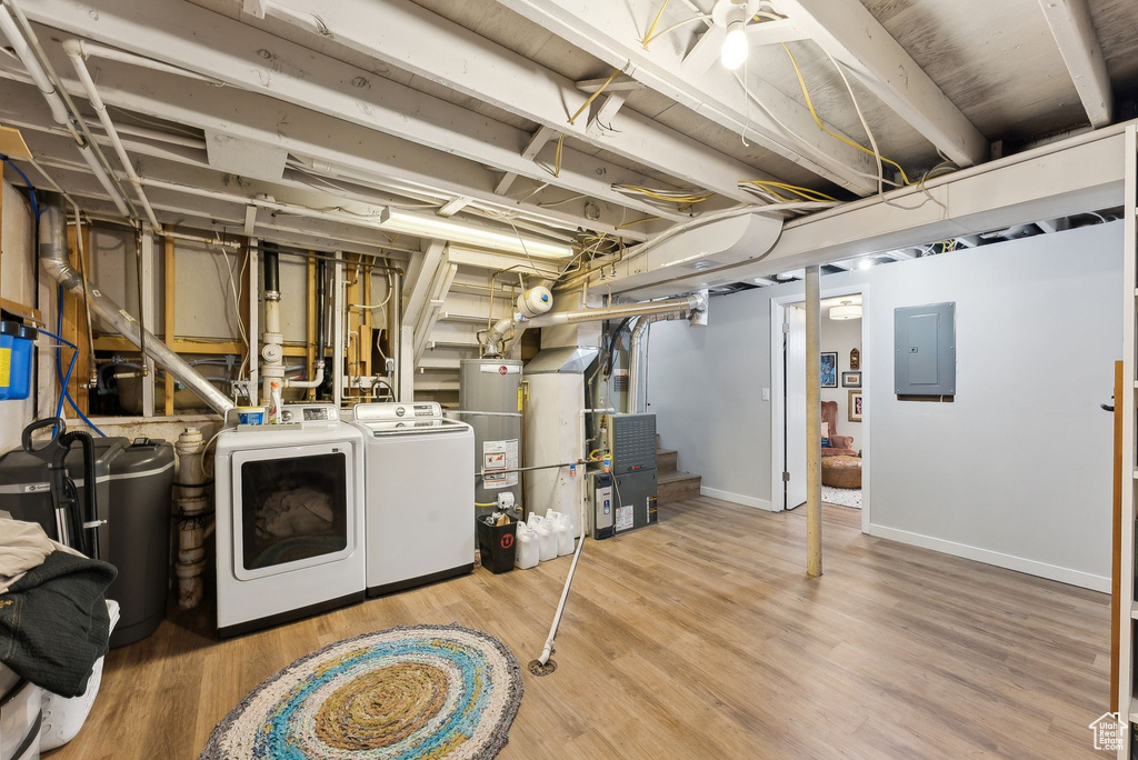 Basement featuring independent washer and dryer, electric panel, gas water heater, baseboards, and wood finished floors