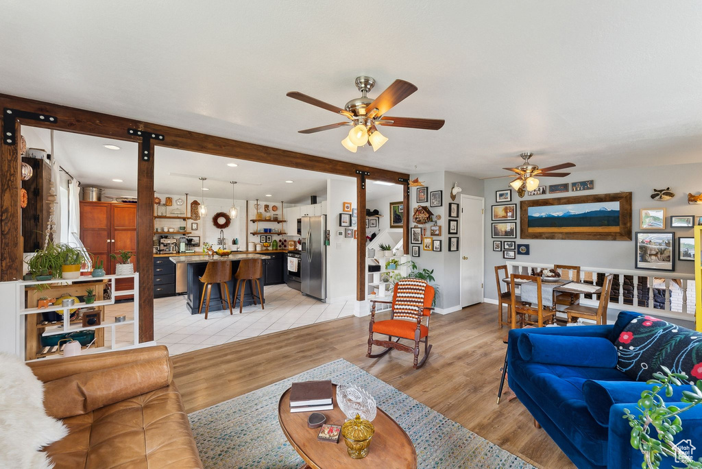Living area featuring a ceiling fan, light wood-style flooring, and baseboards