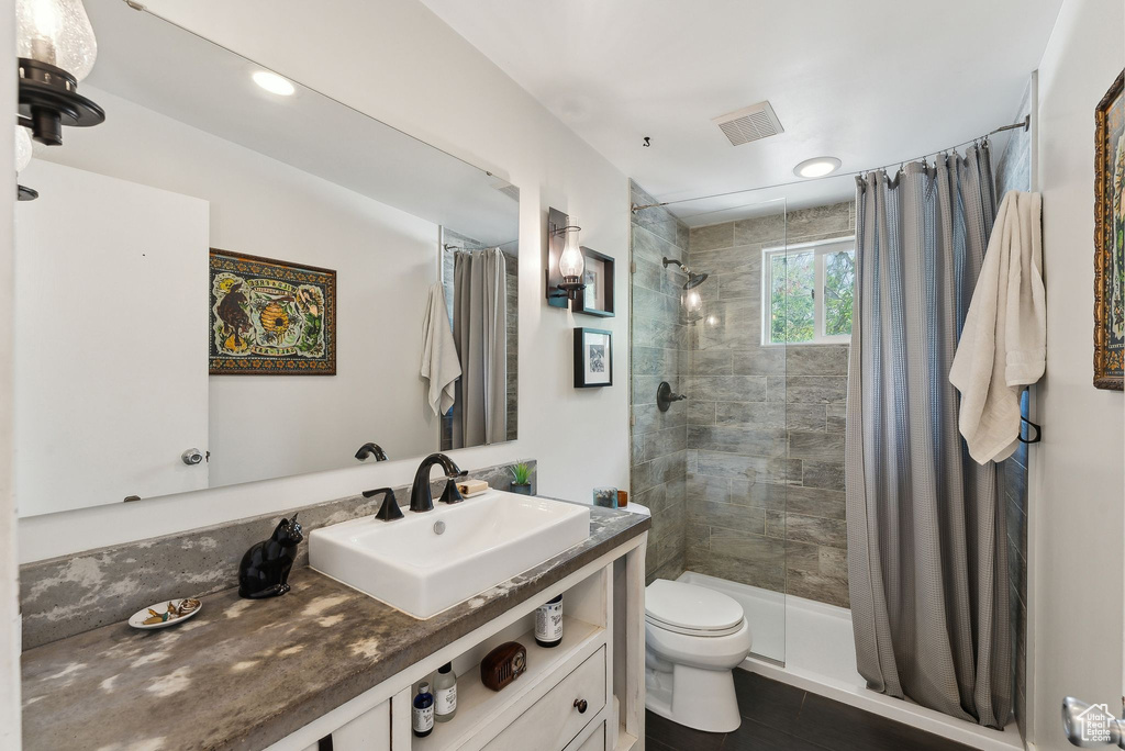 Full bathroom with tiled shower, toilet, and vanity
