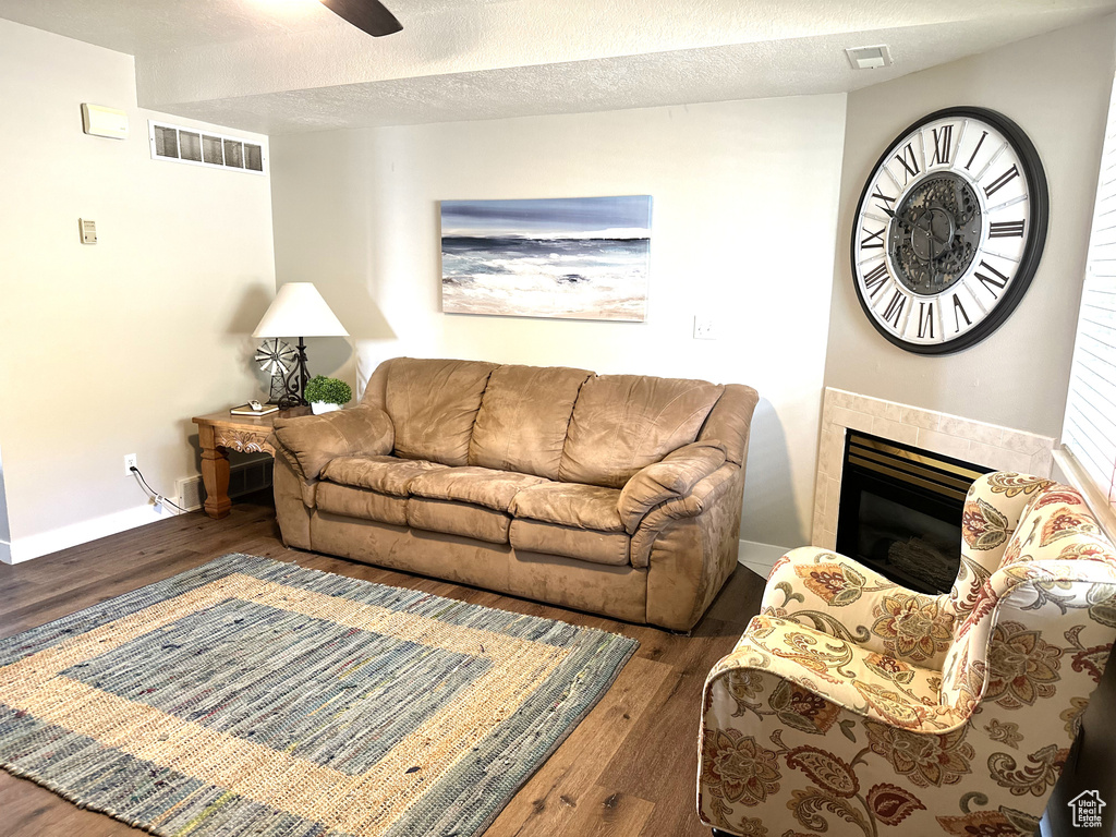 Living room featuring wood finished floors, baseboards, a tile fireplace, and ceiling fan