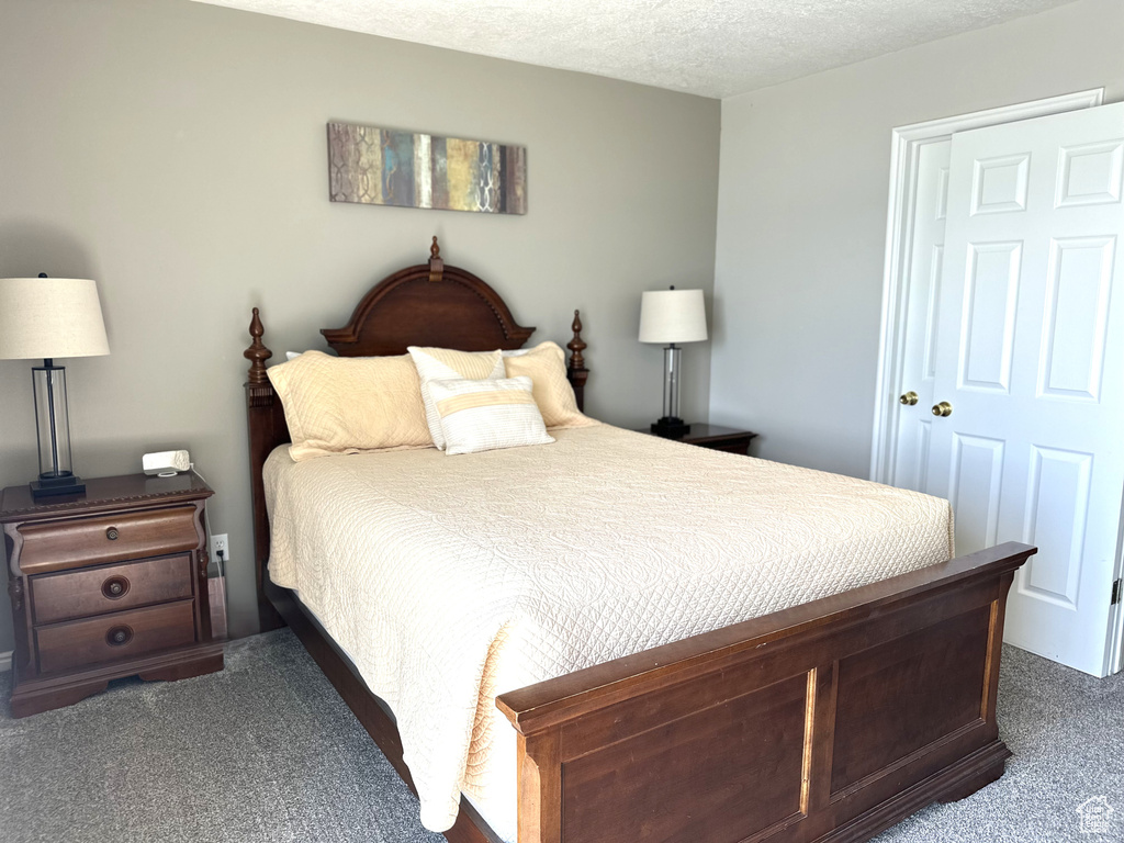 Bedroom with dark colored carpet and a textured ceiling