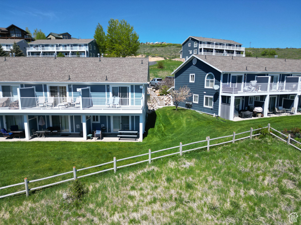 Rear view of property featuring a patio and roof with shingles