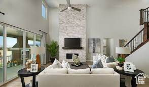 Living room with a towering ceiling, ceiling fan, healthy amount of natural light, a fireplace, and stairway
