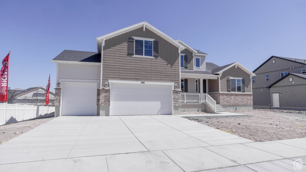 Craftsman inspired home featuring stone siding, concrete driveway, and a garage