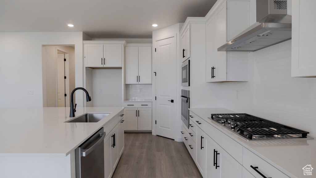 Kitchen with wall chimney range hood, appliances with stainless steel finishes, tasteful backsplash, white cabinetry, and recessed lighting