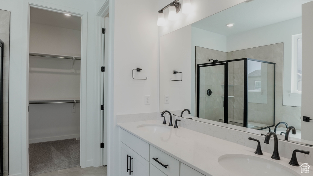 Full bathroom with a stall shower, a walk in closet, double vanity, and tile patterned floors