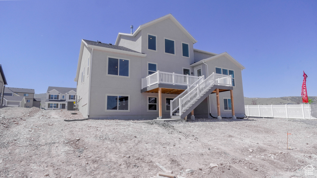 Back of property featuring a wooden deck, stairs, and stucco siding