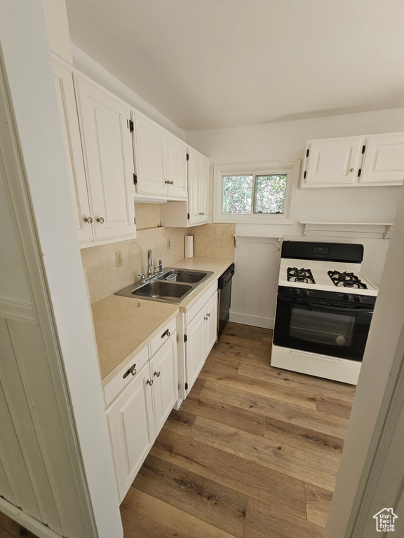 Kitchen featuring range with gas stovetop, a sink, dishwasher, white cabinets, and wood finished floors