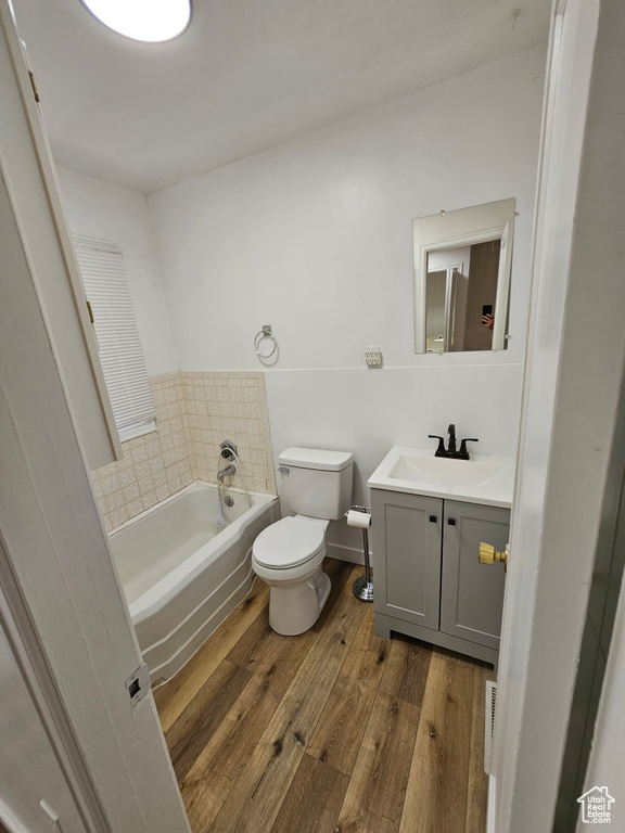 Bathroom with hardwood / wood-style floors, a garden tub, toilet, and vanity