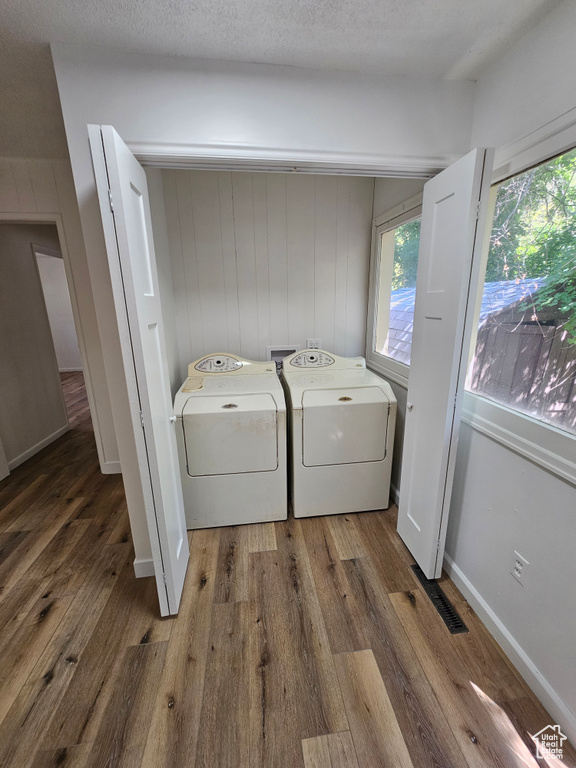 Laundry room with washer and dryer, wood finished floors, and plenty of natural light
